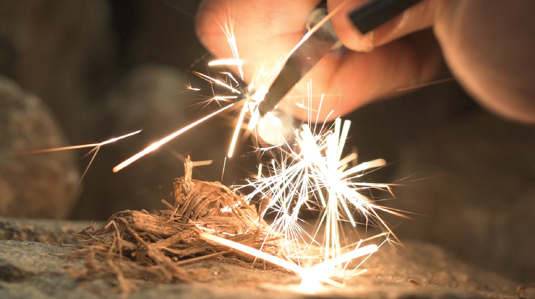 Ferro rod and striker survival tool with emergency whistle making sparks.