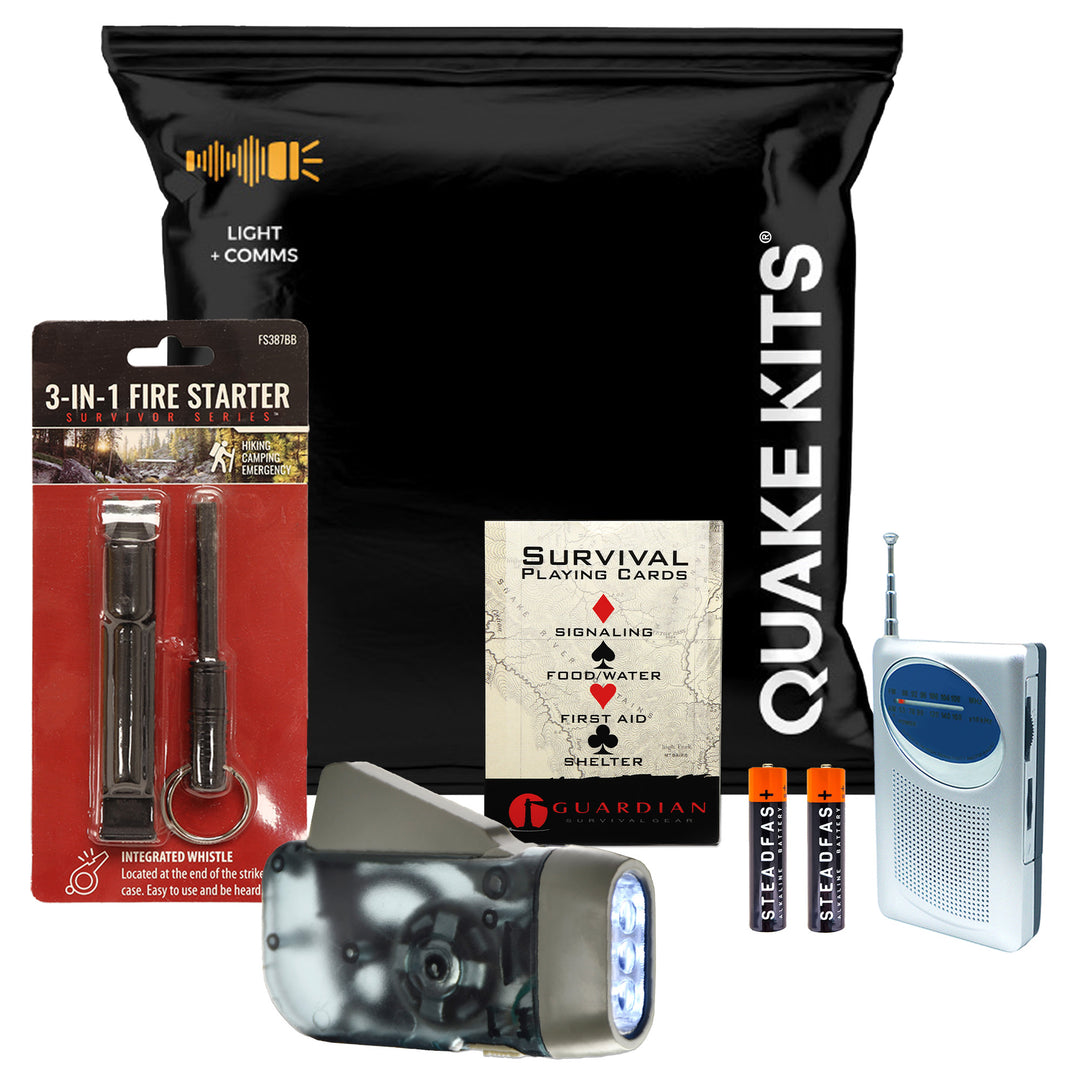 A multi-item emergency preparedness and survival kit set on a plain white background, including a large black bag of Quake Kits, a 3-in-1 fire starter, a flashlight, two batteries, and a portable radio.