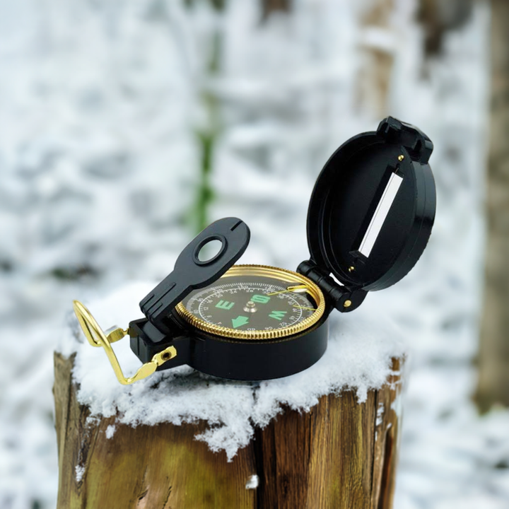 Pocket compass for emergency survival and evacuation. Compass sitting on snow covered log