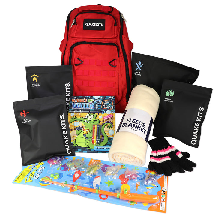 Quake Kits Children's emergency preparedness kit with red backpack, books, blanket, and gloves on a white background. Survival kit for kids. 