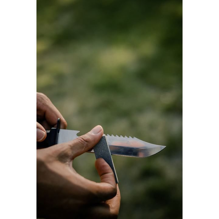 Showing a person sharping Survival knife