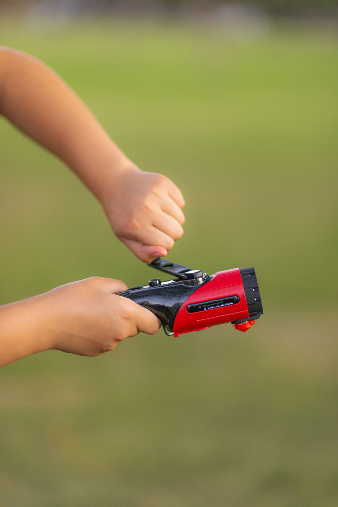 Hand charging the dynamo auto flashlight in a field. Auto rescue tool and flashlight that never needs batteries. 