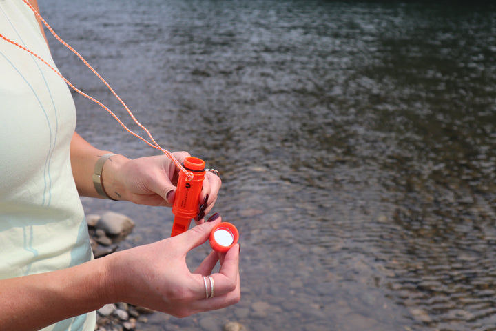 Small orange survival whistle with five essential functions – whistle, compass, signaling mirror, flint, container and a convenient neck lanyard